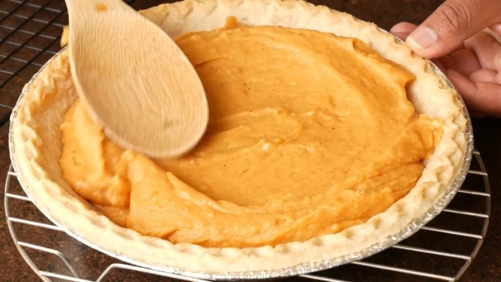 Homemade Sweet Potato Pie Recipe spreading out the pie filling into the crust before baking