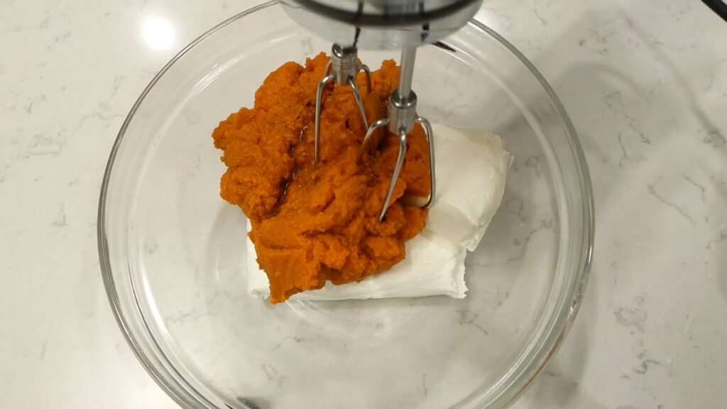 Easy No-Bake Pumpkin Pecan Cheesecake mixing the cream cheese, pumpkin and vanilla