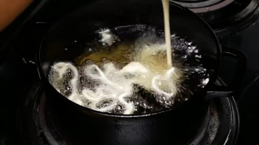 Pouring the funnel cake batter into the hot oil