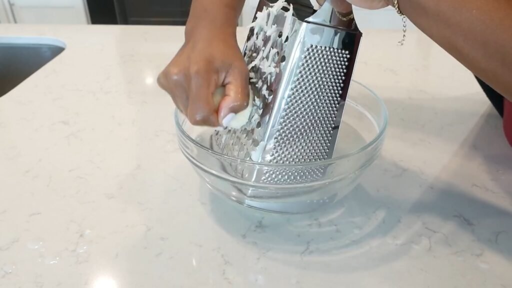 Grating potatoes into a bowl of cool water