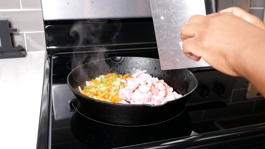 Ham being added to the sautéed veggies